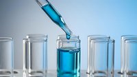 Laboratory pipette dropping blue chemical solution into test tube for scientific research and analysis in modern lab setting.