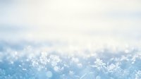 Macro close-up of delicate frost crystals and snowflakes on a winter surface with soft blue and white bokeh background, suitable for seasonal designs and winter themes.