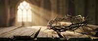 Crown of thorns resting on wooden table inside cathedral with stained glass window and light rays streaming through, symbolizing Christ's passion and resurrection for religious artwork.