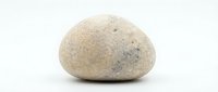 Natural smooth river stone with speckled texture isolated on white background for spa wellness meditation zen garden landscaping design projects.