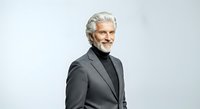 Mature man with gray hair and beard wearing dark blazer and turtleneck, isolated on white background for corporate, business, and professional design projects.