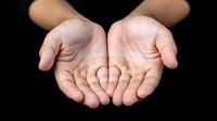 Cupped hands held together against dark background showing empty palms in giving or receiving gesture, symbolizing care, support and charity concept.