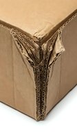 Damaged brown cardboard box corner showing torn corrugated layers and internal structure on white background for packaging and shipping concepts.