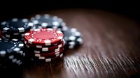 Stack of red and black gaming tokens on wooden surface with dramatic lighting and shallow depth of field, creating moody atmosphere for casino and gambling concepts.