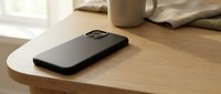 Modern black smartphone case on wooden desk with coffee mug and notebook in soft natural lighting for technology and workspace concepts.