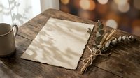 Blank paper sheet with dried eucalyptus bouquet on wooden table with warm sunlight shadows creating cozy workspace atmosphere for writing letters.