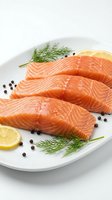 Fresh raw salmon fillets on white plate with lemon slices, dill herbs and black peppercorns for healthy cooking and gourmet seafood preparation.