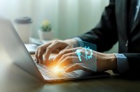 Businessman hands typing on laptop with glowing digital security shield icon overlay representing cybersecurity and data protection in modern office.