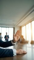Business professional raising hand during corporate meeting in modern conference room with colleagues in background.