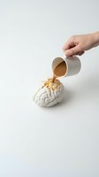 Hand pouring coffee from white mug onto brain model on clean background representing caffeine addiction and mental stimulation concepts.