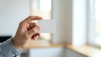 Male hand holding blank white business card in modern office environment with natural light and blurred background for branding and corporate identity projects.
