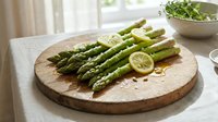 Fresh green asparagus spears arranged on wooden cutting board with lemon slice, healthy vegetable preparation for cooking in bright kitchen setting.