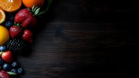 Fresh mixed berries, citrus fruits and juicy oranges arranged on dark wooden background with copy space for text, food photography styling.