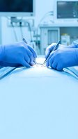 Surgeon hands in blue gloves performing precise surgical procedure with instruments in modern operating room with medical equipment background.