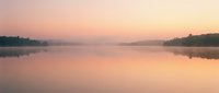 Serene lake at sunrise with soft pink and orange hues reflecting on calm water, misty forest silhouettes along shoreline, peaceful dawn landscape for nature and wellness projects.
