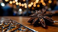 Star anise spice on wooden surface with blurred bokeh lights in background creates cozy festive atmosphere for holiday baking and seasonal recipes.