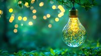 Glowing light bulb with magical sparkles inside against blurred green foliage and bokeh lights background creates dreamy atmosphere for creative design.
