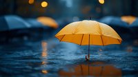 Orange umbrella standing in rain with blurred bokeh lights and water reflections creating atmospheric moody scene for weather and protection concepts.