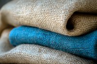 Folded natural linen and bright blue burlap fabric layers showing detailed textile texture and weave pattern in macro photography. For interior design and craft projects.