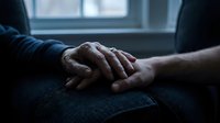 Two people holding hands in comfort and support, showing compassion and emotional connection during difficult moments or counseling sessions.