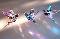 Geometric crystal hummingbirds with iridescent rainbow colors flying in formation against blurred background with prismatic light effects and bokeh.