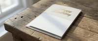 Elegant white greeting card with gold foil Happy Birthday text on rustic wooden table surface for celebration design and party invitations.