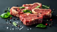 Raw T-bone steaks with fresh herbs, salt, and peppercorns on dark background, ready for cooking. Perfect for gourmet food photography.