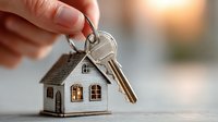 Hand holding house keys with miniature home keychain symbolizing real estate ownership, property purchase, mortgage approval, and new homeowner success.