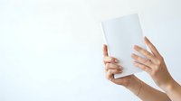Two hands holding blank white tablet or clipboard against neutral background for mockup and branding purposes.