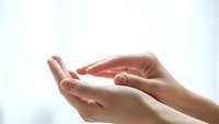 Gentle cupped hands in protective gesture against soft white background, symbolizing care, support and healing in healthcare and wellness concepts.