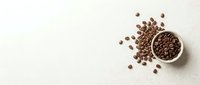 Roasted coffee beans scattered around a ceramic bowl on neutral background, overhead view for beverage, cafe, and food industry design projects.