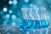 Laboratory glass flasks with bright blue liquid on reflective surface against blurred bokeh background, scientific research concept in modern chemistry lab.