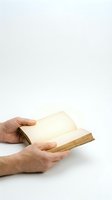 Hands holding open vintage book with blank yellowed pages on white background for reading and literature concepts.