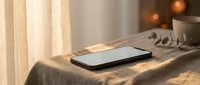 Modern smartphone lying on soft bedding in warm sunlit bedroom with cozy morning atmosphere for technology and lifestyle concepts.