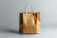 Brown paper shopping bag with white twisted handles on neutral gray background, minimalist composition for retail and packaging design concepts.