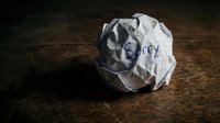 Crumpled paper ball with the word Sorry written on it, lying on a wooden surface, symbolizing regret, apology, and failed communication.