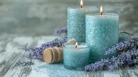 Glowing turquoise candles surrounded by fresh lavender sprigs on rustic wooden surface create serene spa atmosphere with natural elements and soft illumination.
