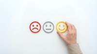 Caucasian hand selecting yellow smiley face among sad and neutral emoji icons on white background, representing customer satisfaction, feedback and service rating for business surveys.