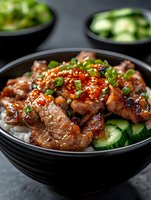 Glazed teriyaki pork bowl with steamed rice, fresh cucumber slices and green onions. Sweet and savory meat garnished with sesame seeds and chili flakes served in black bowl.