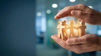 Hands protecting wooden figures in circle, symbolizing teamwork, unity, community support, and group collaboration in business environment.