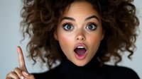 Young woman with curly hair expressing extreme surprise with open mouth and raised finger against light background. For advertising and social media content.