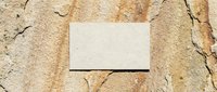 Blank white business card mockup on weathered stone surface with natural cracks and warm earth tones for branding design projects.