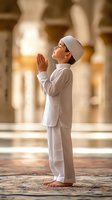 Young Middle Eastern boy in traditional white clothing and prayer cap standing in prayer position with raised hands inside mosque during Ramadan worship.