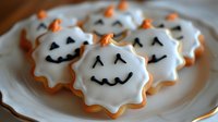 Halloween ghost cookies with white icing and smiling faces on plate, festive autumn treats for spooky season celebrations and holiday baking.