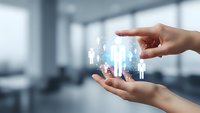 Hands protecting glowing human figures in modern office environment representing HR management, employee care and workforce protection concepts.