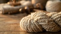 Natural jute rope coils on rustic wooden surface for crafting, nautical decor, and DIY projects with warm lighting and textured background.
