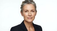 Mature woman with gray hair wearing black blazer against white background, professional headshot for business, corporate, and executive use.