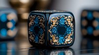 Black gaming dice with ornate blue and gold pattern featuring intricate floral designs and decorative elements against dark background with soft bokeh effect.