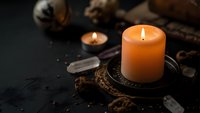 Autumn candle burning on dark surface with pine cones, crystals and natural elements creating cozy seasonal atmosphere for home decor and relaxation.