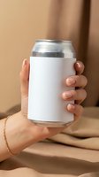 Female hand holding aluminum beverage can with blank white label mockup for branding and product design on neutral beige background.